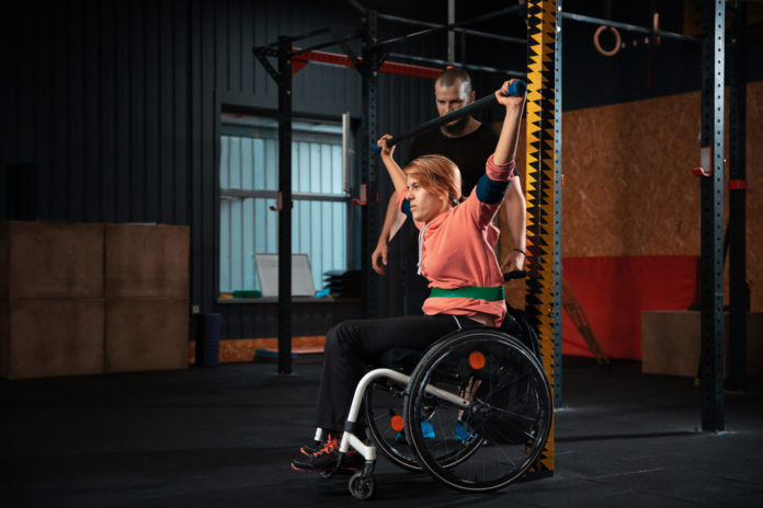 Woman in a wheelchair working out with a trainer