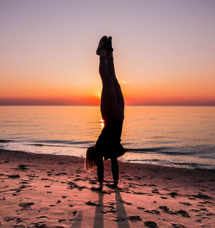 Woman doing a handstand on the beach